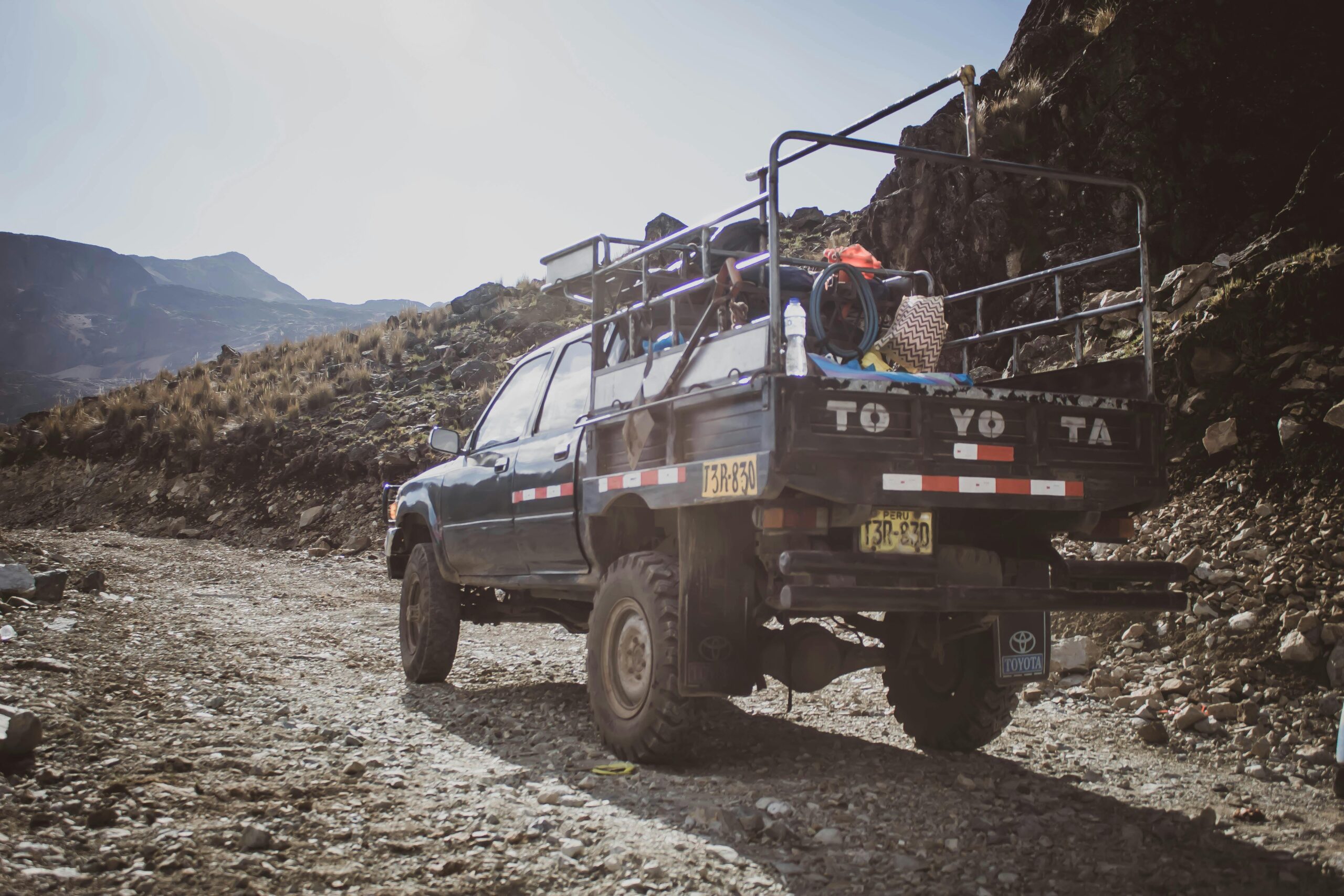 Toyota pickup truck navigating rocky unpaved road in remote Peru mountains.