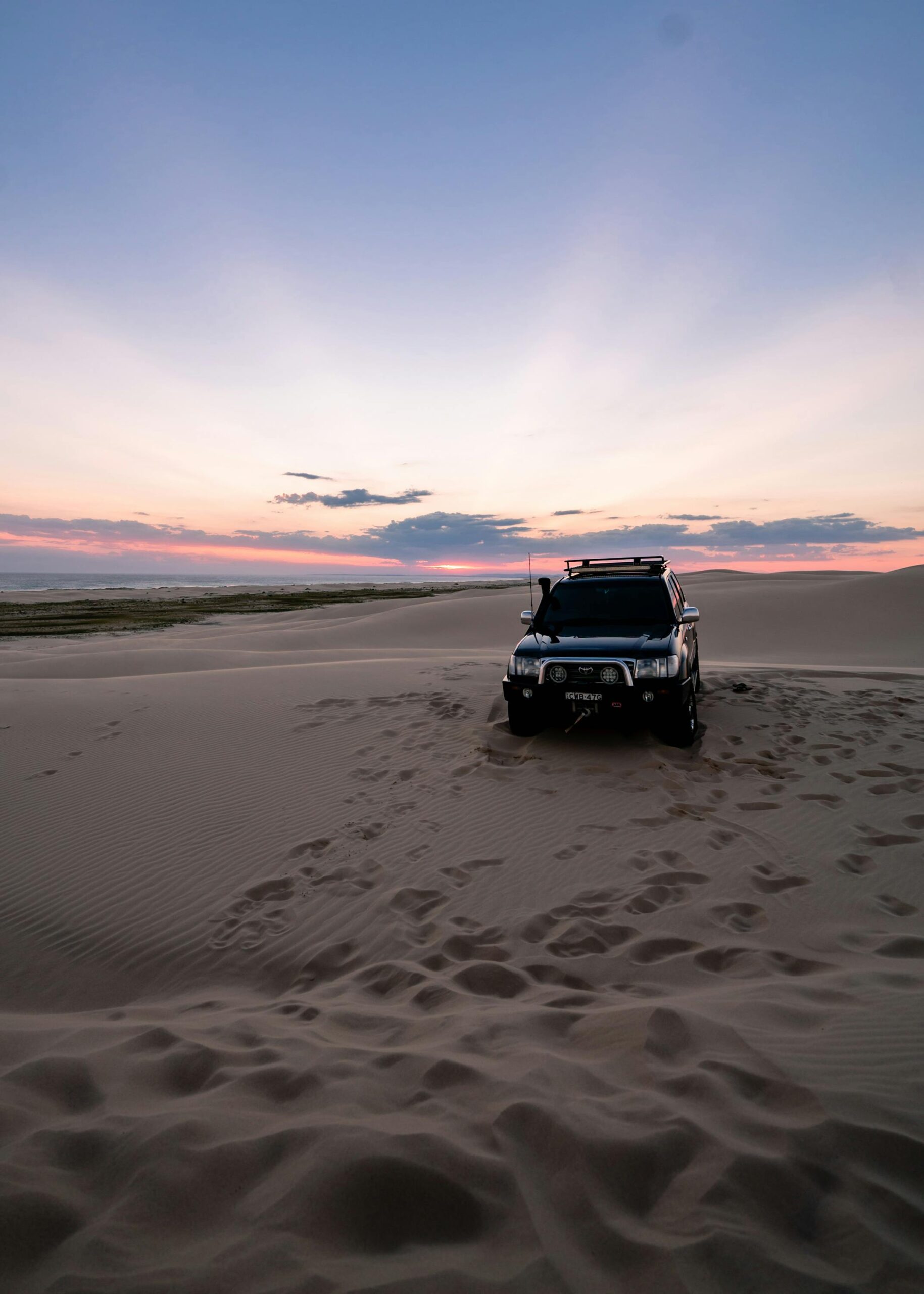 A 4x4 vehicle captures the spirit of adventure against a stunning desert sunset in Australia.