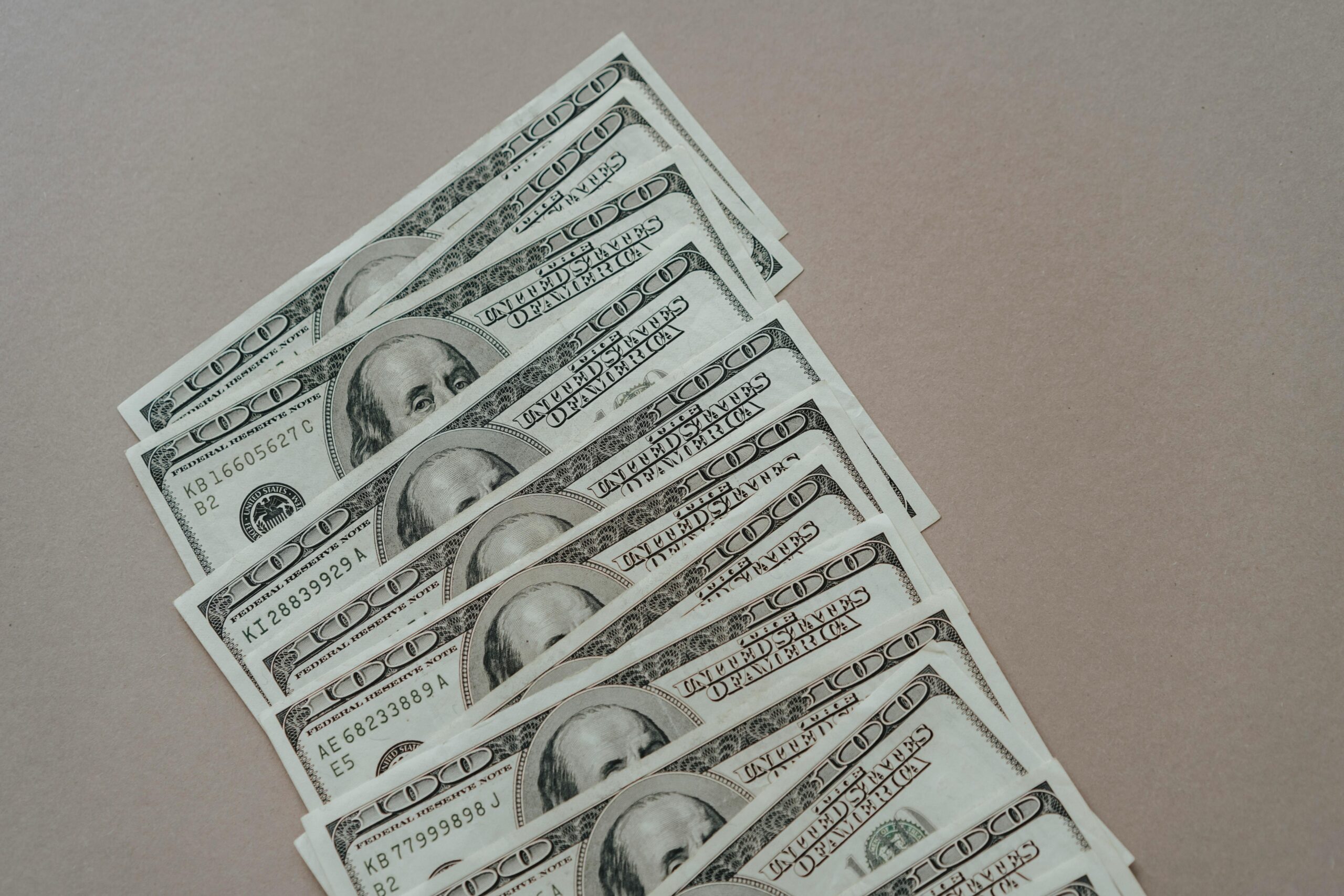 A close-up of multiple US dollar bills arranged on a neutral surface.
